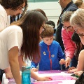 Child in focus in the middle doing a jigsaw puzzle of a histology slide with adults around the table looking down