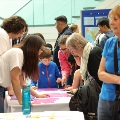 Child in focus in the middle doing a puzzle of a histology slide surrounded by people around a table